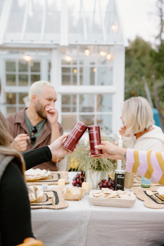 People enjoying non-alcoholic wine from Just Enough Wines at an outdoor social gathering.
