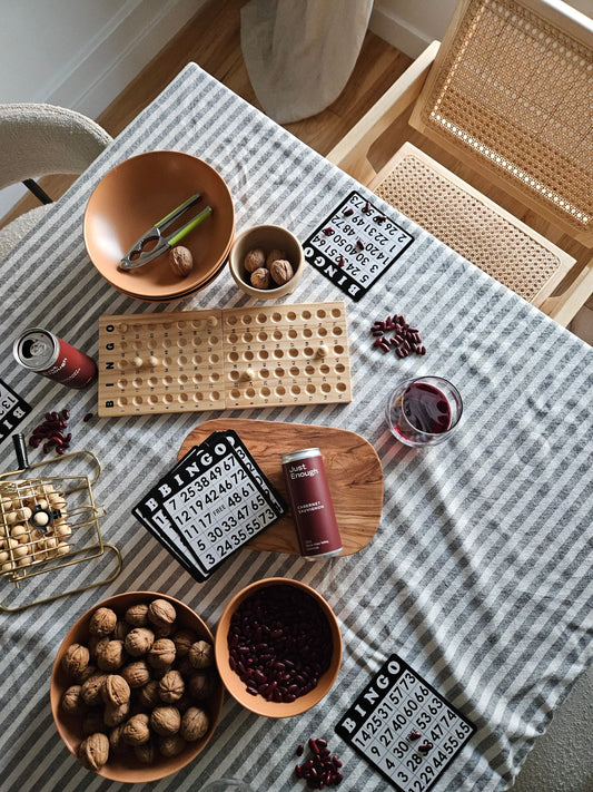 Just Enough Wines Cabernet Sauvignon can displayed on a game night table with bingo cards, walnuts, and glasses of red wine.