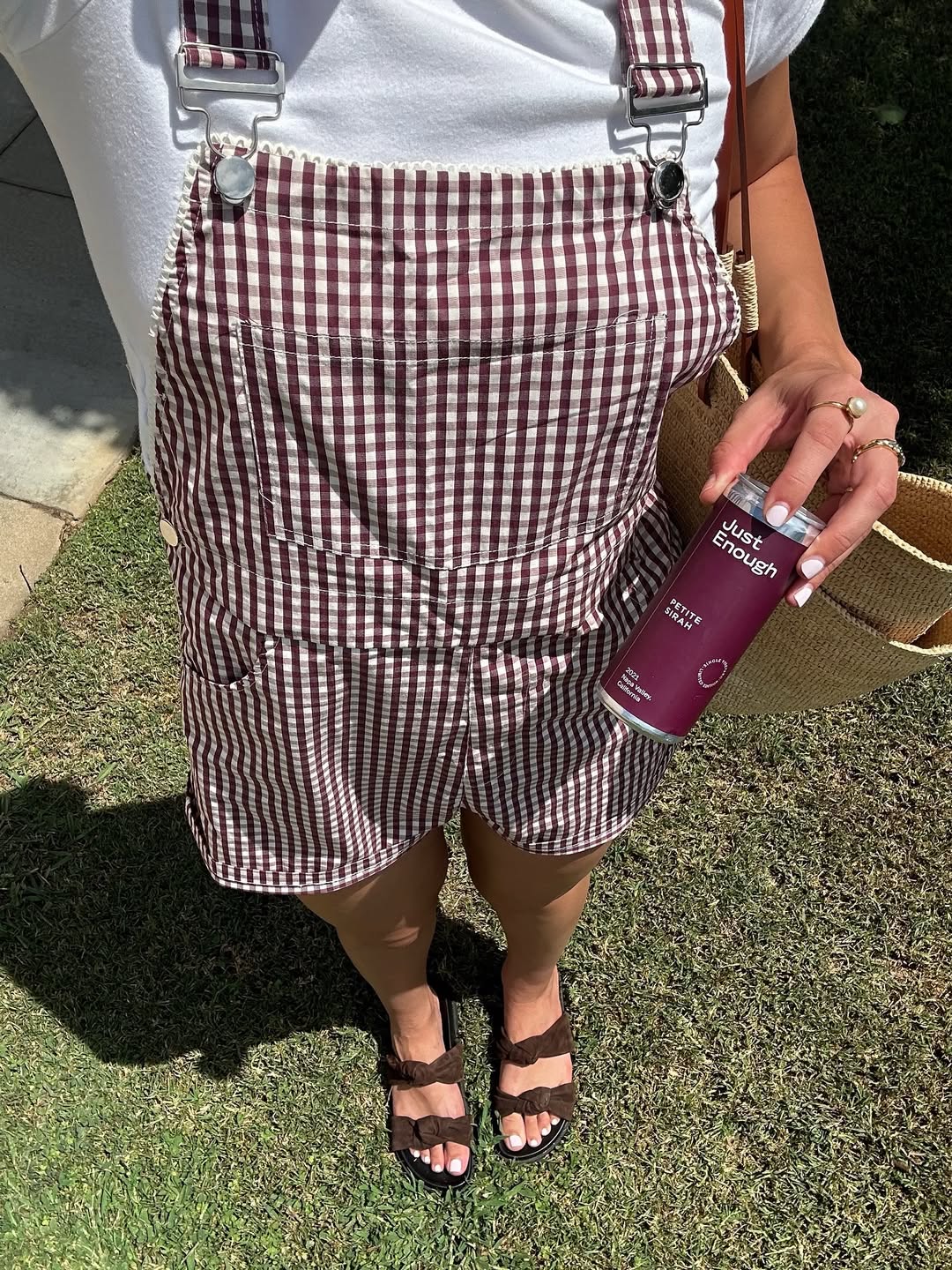 Woman standing outdoors holding a can of Petite Sirah from Just Enough Wines.