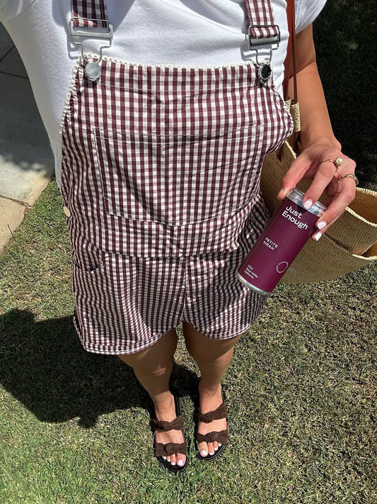 Woman standing outdoors holding a can of Petite Sirah from Just Enough Wines.