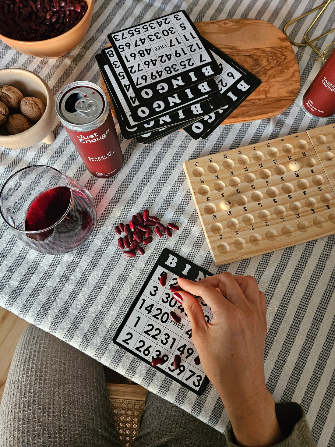 Wine bingo game at home with red wine glass and Just Enough Wines Cabernet Sauvignon can